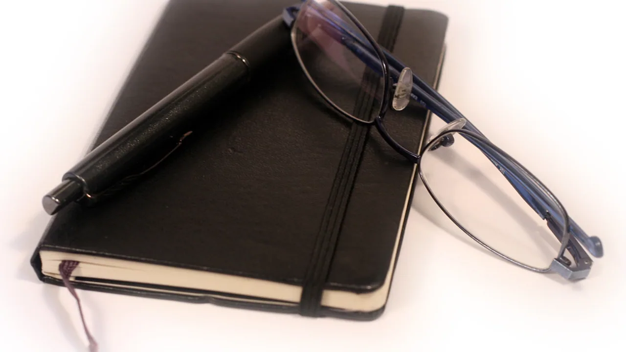Diary, pen, and glasses on a planning desk
