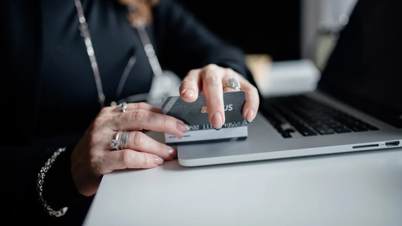 Person completing an online payment beside a laptop